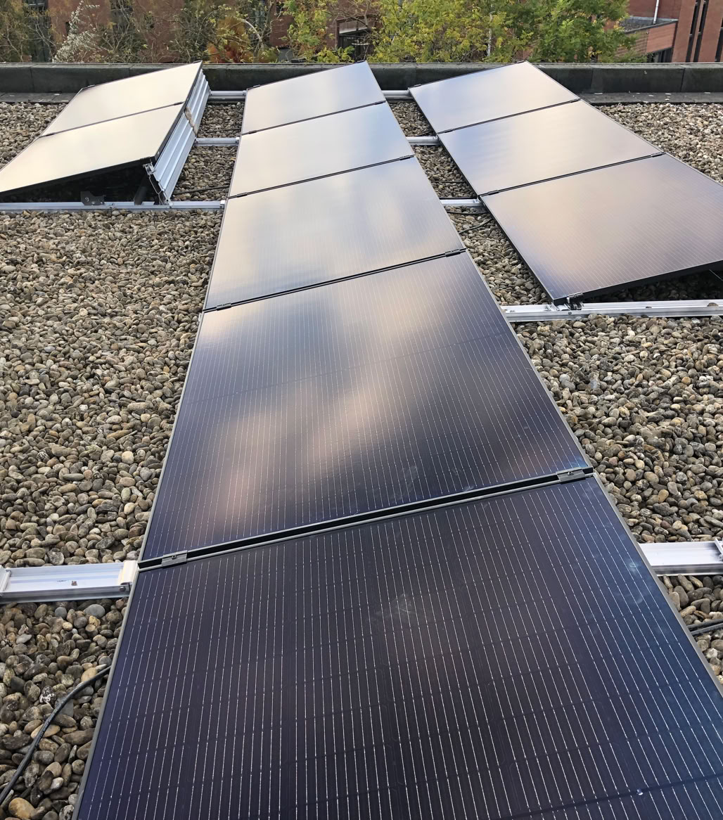 Zonnepanelen op een grinddak met gebouwen op de achtergrond.